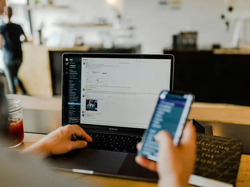 Person managing social media on a phone and laptop